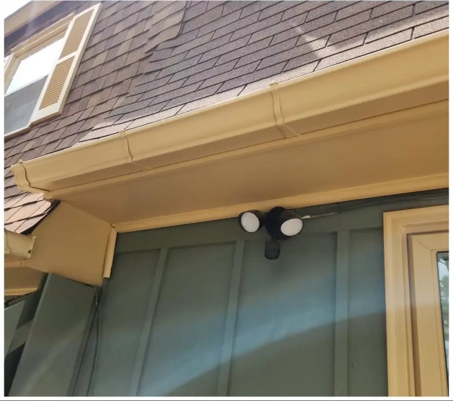 After: bright yellow gutters, soffit, and fascia on a green-sided home