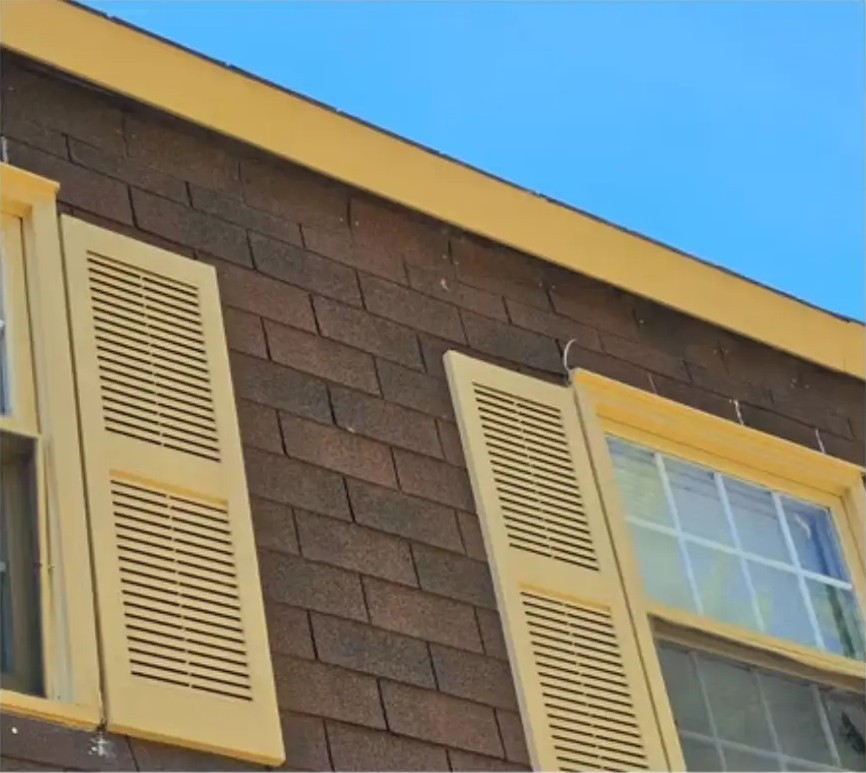 After exterior painting: mustard-yellow roofline trim and shutters